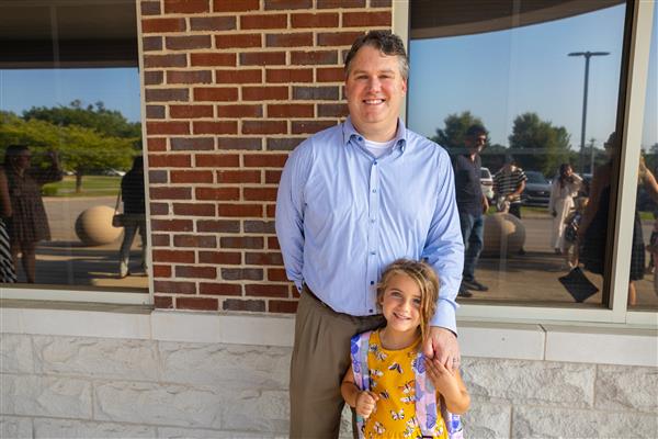 dad and girl student smiling in front of building